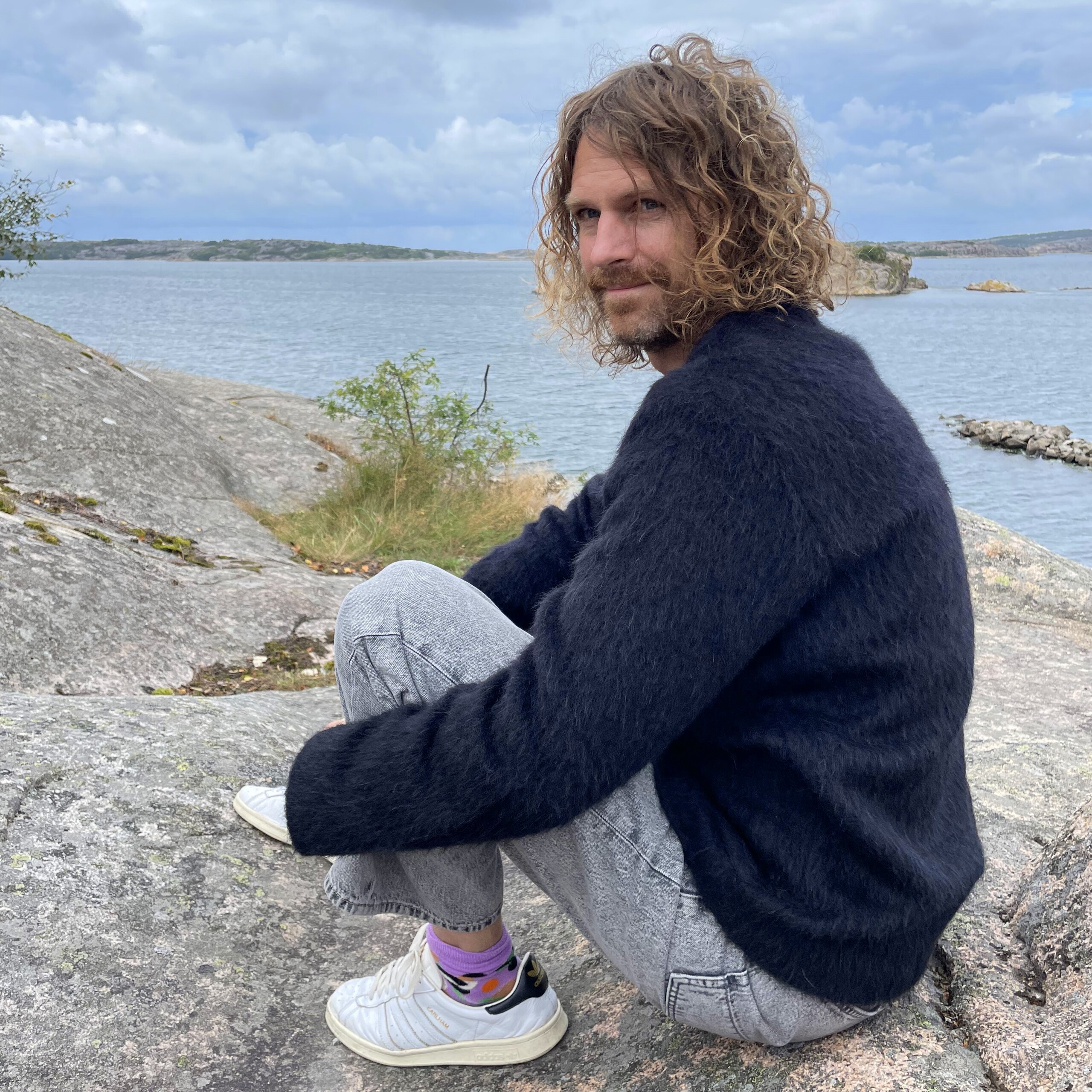 dj sitting on the sea shore